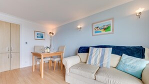 A room with a dining table, a sofa, and a wall-mounted lamp. - 1 Bed in Saundersfoot (oc-pw9247) (Saundersfoot)