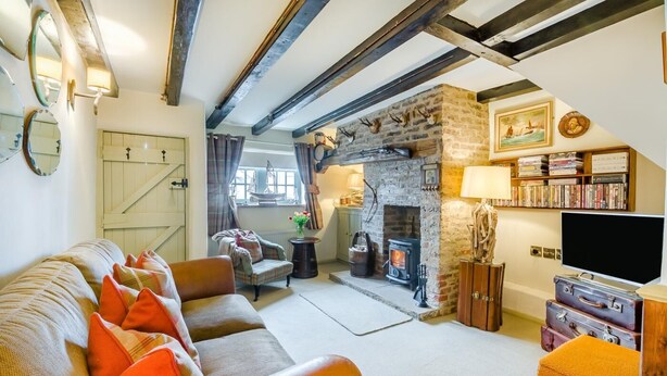 A cozy living room with a fireplace, a sofa with orange cushions, a bookshelf, and a television. - 1 Bed in Redcar (oc-cl003) (Redcar)