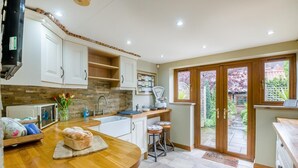 A kitchen with a wooden countertop, a sink, a microwave, and a window with a view of a garden. - 1 Bed in Redcar (oc-cl003) (Redcar)