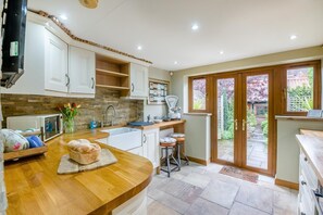 A kitchen with a wooden countertop, white cabinets, a built-in oven, and a view of the garden through glass doors. - 1 Bed in Redcar (oc-cl003) (Redcar)