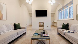 Un salon moderne avec deux canapés, une table basse, un téléviseur à écran plat et une cheminée.