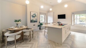 A modern kitchen with a central island, pendant lighting, and a dining area with a round table and chairs. - 3 Bed in Buxton (oc-c33947) (Buxton)