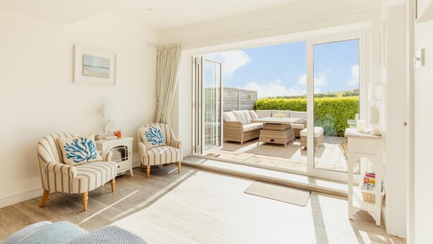 A spacious living area with a sofa, armchairs, and a dining table. - 4 Bed in Little Petherick (oc-urchpe) (Little Petherick)