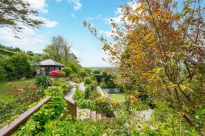 Ein Garten mit einem Gartenhaus, verschiedenen Pflanzen und einem Weg.