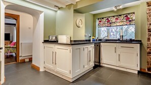 A kitchen with white cabinets, a black countertop, and a window with a floral curtain.