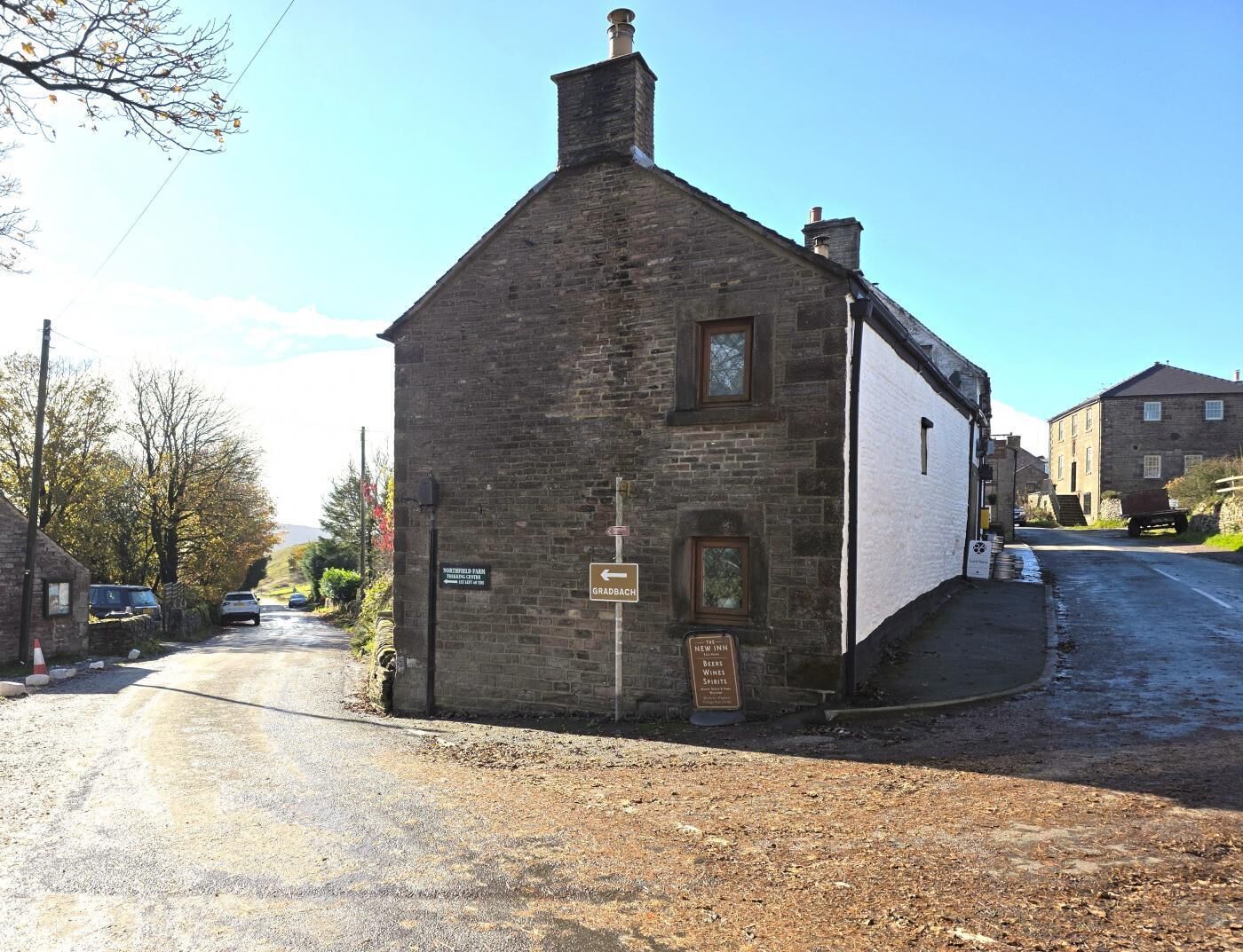 Un bâtiment traditionnel en pierre, avec une enseigne indiquant « The New Inn » et un panneau indicateur pointant vers « Grabsbach ».