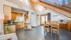 A modern kitchen with wooden cabinets, a dining area with a table and chairs, and a skylight. - 2 Bed in Dolgellau (oc-bow282) (Blaenau Ffestiniog)