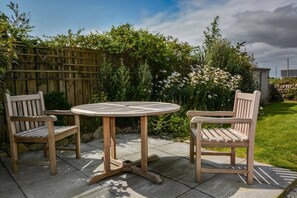 Een houten tafel met twee stoelen in een tuin.