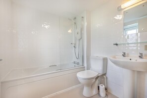 Een moderne badkamer met een douchecabine van glas, een wit toilet en een wastafel met spiegel erboven.