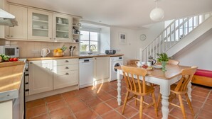 Une cuisine moderne avec des meubles blancs, une table à manger en bois et un escalier.