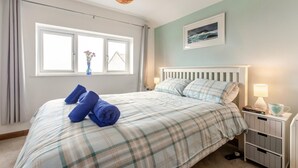 Ein Schlafzimmer mit einem Bett, zwei Nachttischen, einem Fenster und einem Wandbild.