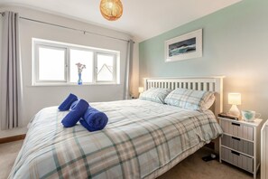 Ein Schlafzimmer mit einem Bett, zwei Nachttischen, einem Fenster und einem Wandbild.