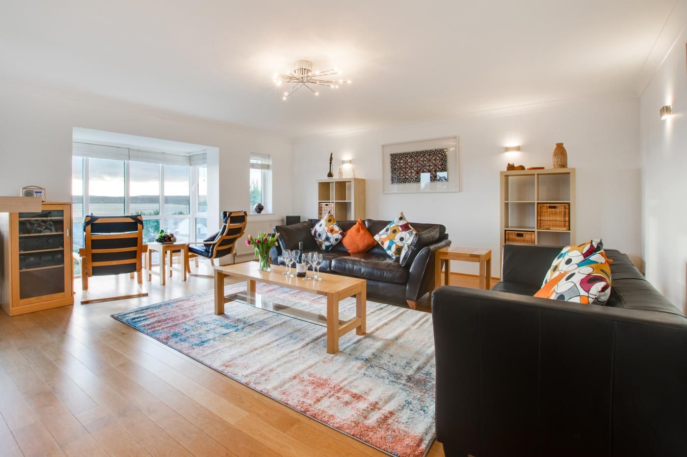 A modern living room with a sofa, chairs, a coffee table, and a bookshelf.