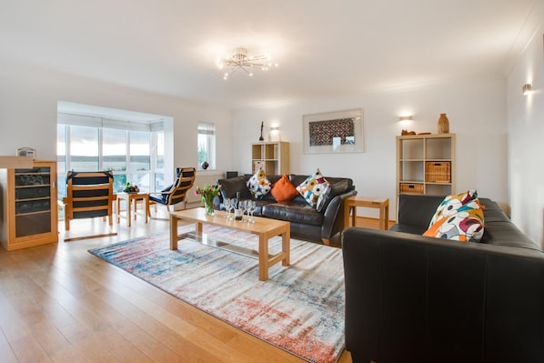A modern living room with a sofa, chairs, a coffee table, and a bookshelf. - 4 Bed in Marazion (oc-gwynsa) (Marazion)