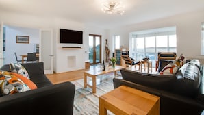 A modern living room with a black sofa, wooden coffee table, and a flat-screen TV mounted on the wall. - 4 Bed in Marazion (oc-gwynsa) (Marazion)