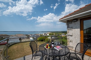 A balcony with a table set for two, overlooking a coastal view. - 4 Bed in Marazion (oc-gwynsa) (Marazion)