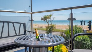 A balcony with a table, a bottle of champagne, and glasses.