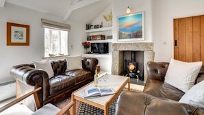 A cozy living room with leather sofas, a fireplace, and bookshelves. - 3 Bed in Sennen (oc-thbyre) (Sennen)