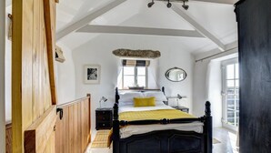 A bedroom with a large bed, wooden paneling, a window, and a mirror. - 3 Bed in Sennen (oc-thbyre) (Sennen)