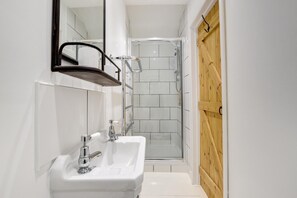 Ett modernt badrum med ett vitt handfat, en spegel och en duschkabin.