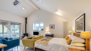 Moderni hotellihuone, jossa on sänky, sohva, televisio ja parveke.