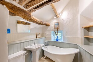 A bathroom with a freestanding bathtub, a sink, and a toilet. There is a window with a view of greenery outside. - 4 Bed in Staveley (oc-s33928) (Staveley)