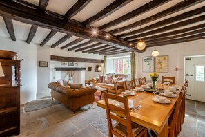 A dining area with a wooden table set for six, flanked by wooden chairs. A brown leather sofa is positioned against the wall, and a wooden cabinet is visible to the left. - 4 Bed in Staveley (oc-s33928) (Staveley)