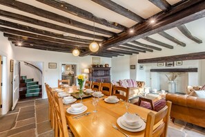 A dining area with a wooden table set for six, surrounded by wooden chairs. A staircase is visible in the background leading to another room. - 4 Bed in Staveley (oc-s33928) (Staveley)