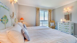 A bedroom with two beds, a dresser, a chair, and a window with curtains. - 3 Bed in Mevagissey (oc-windru) (Mevagissey)