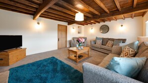 A living room with a wooden ceiling, a flat-screen TV, a coffee table, a sofa, and a rug. - 3 Bed in Askrigg (oc-ds1049) (Askrigg)