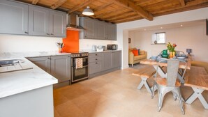 A modern kitchen with grey cabinets, a wooden ceiling, and a dining area with a wooden table and chairs. - 3 Bed in Askrigg (oc-ds1049) (Askrigg)