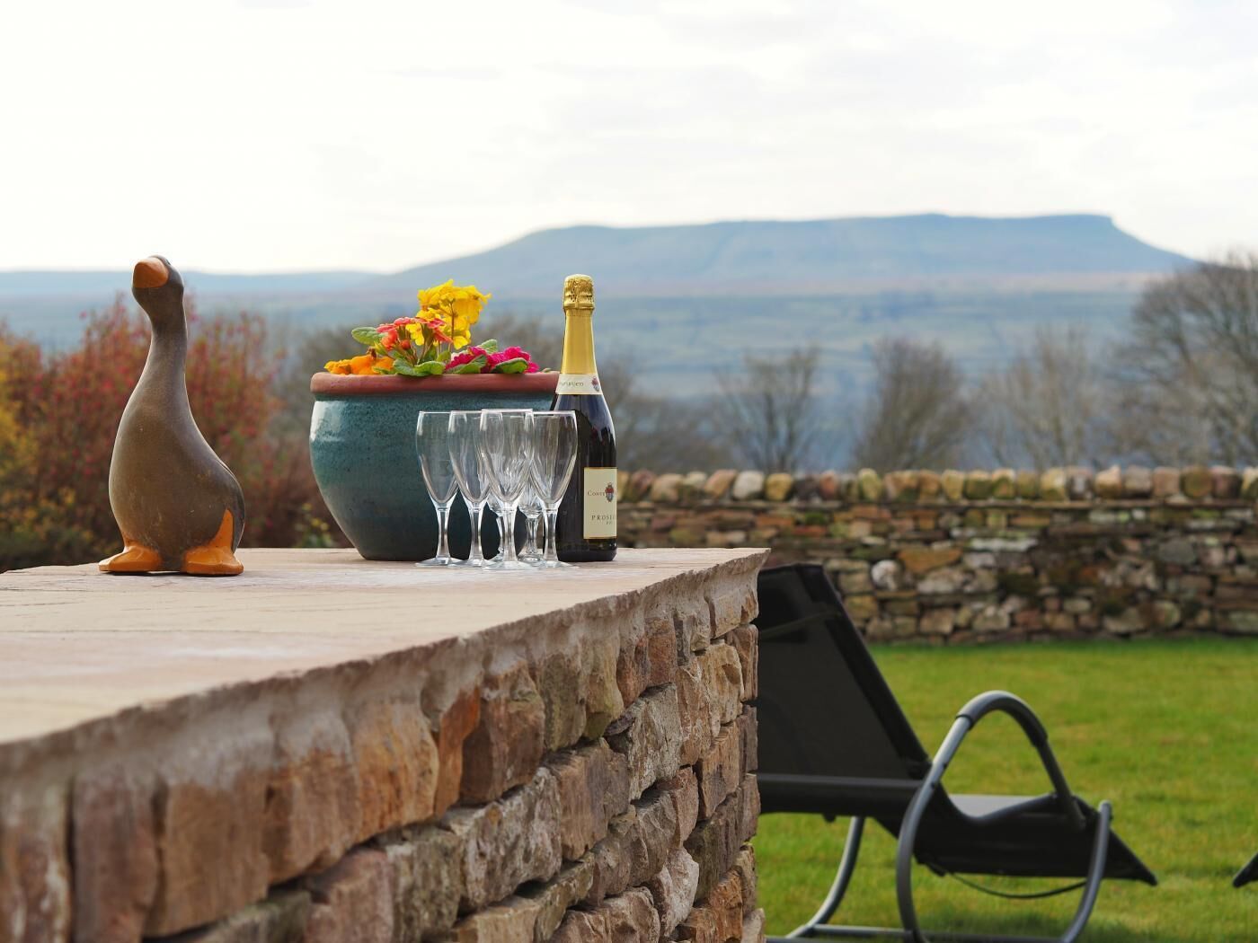 A stone table with a bottle of wine, glasses, and a decorative penguin figure.
