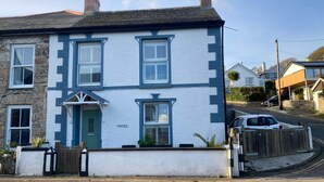 A two-story house with a white and blue exterior, a green door, and a nameplate reading "NIGEL". - 2 Bed in Mousehole (oc-nigelh) (Mousehole)