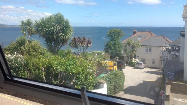 A coastal view with a road, parked cars, and buildings. - 2 Bed in Mousehole (oc-nigelh) (Mousehole)