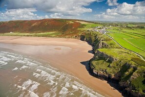 Un paysage côtier comprenant une plage de sable, des falaises et un petit village.