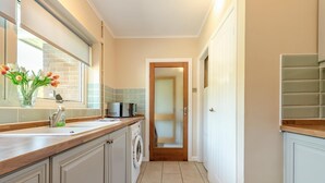 A kitchen with a washing machine, a microwave, and a cabinet with a glass door. - 2 Bed in Port Eynon (oc-hh2104) (Port Eynon)