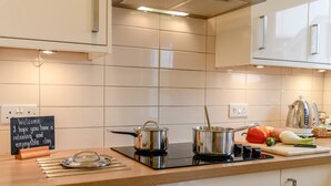 A modern kitchen with two pots on a stove, a cutting board with vegetables, and a sign that reads "Welcome I hope you have a relaxing and enjoyable stay." - 3 Bed in Christchurch (oc-r27894) (Christchurch)