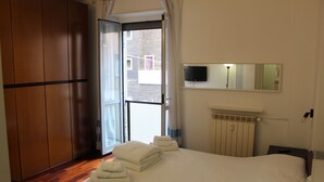 A hotel room with a bed, a TV mounted on the wall, and a view of the outside through a door. - Three-room In Tortona District (Milano)