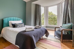 A bedroom with a bed, a chair, a window, and curtains. - 7 Bed in Mousehole (oc-boslan) (Paul)