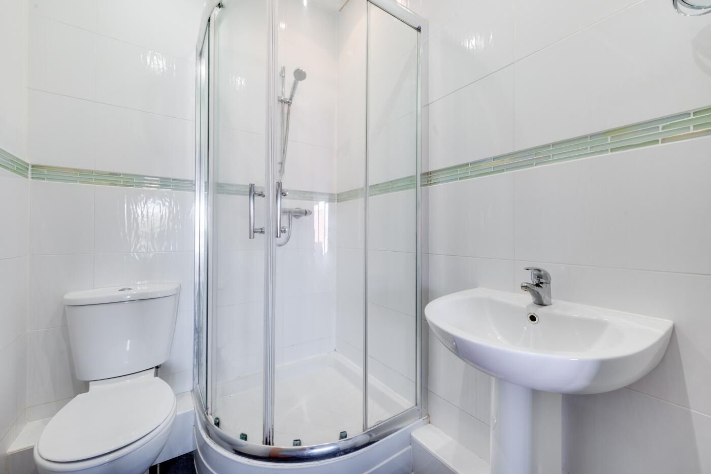 A bathroom with a glass-enclosed shower, a white toilet, and a pedestal sink.