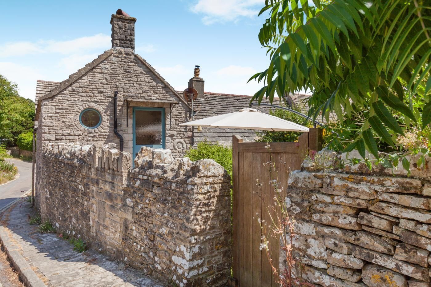 A stone cottage with a chimney, a wooden door, and a garden.