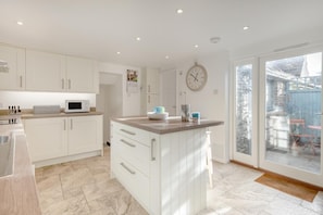 A modern kitchen with white cabinetry, a central island, and a large window. - 2 Bed in Worth Matravers (oc-q33640) (Worth Matravers)
