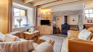 Una sala de estar acogedora con chimenea de piedra, muebles de madera y un televisor.