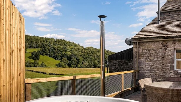A hot tub on a balcony with a view of a green landscape and a stone building. - 3 Bed in Barden (oc-s33752) (Barden)