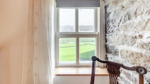 A room with a stone wall, a window with a view of a green field, and a wooden chair. - 3 Bed in Barden (oc-s33752) (Barden)