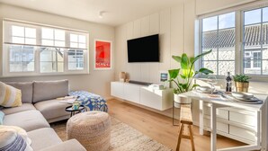 Un soggiorno moderno con un divano, un tavolino, una TV e un'area pranzo con un tavolo apparecchiato per due persone.