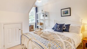 Ein Schlafzimmer mit einem Bett, einem weißen Kleiderschrank, einem Fenster und einem gerahmten Bild an der Wand.