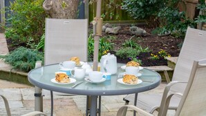 A round glass table with chairs, a yellow umbrella, and a garden setting. - 2 Bed in Holt (oc-2274) (Holt)