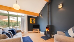 A cozy living room with a fireplace, comfortable seating, and a large window. - 2 Bed in Holt (oc-2274) (Holt)