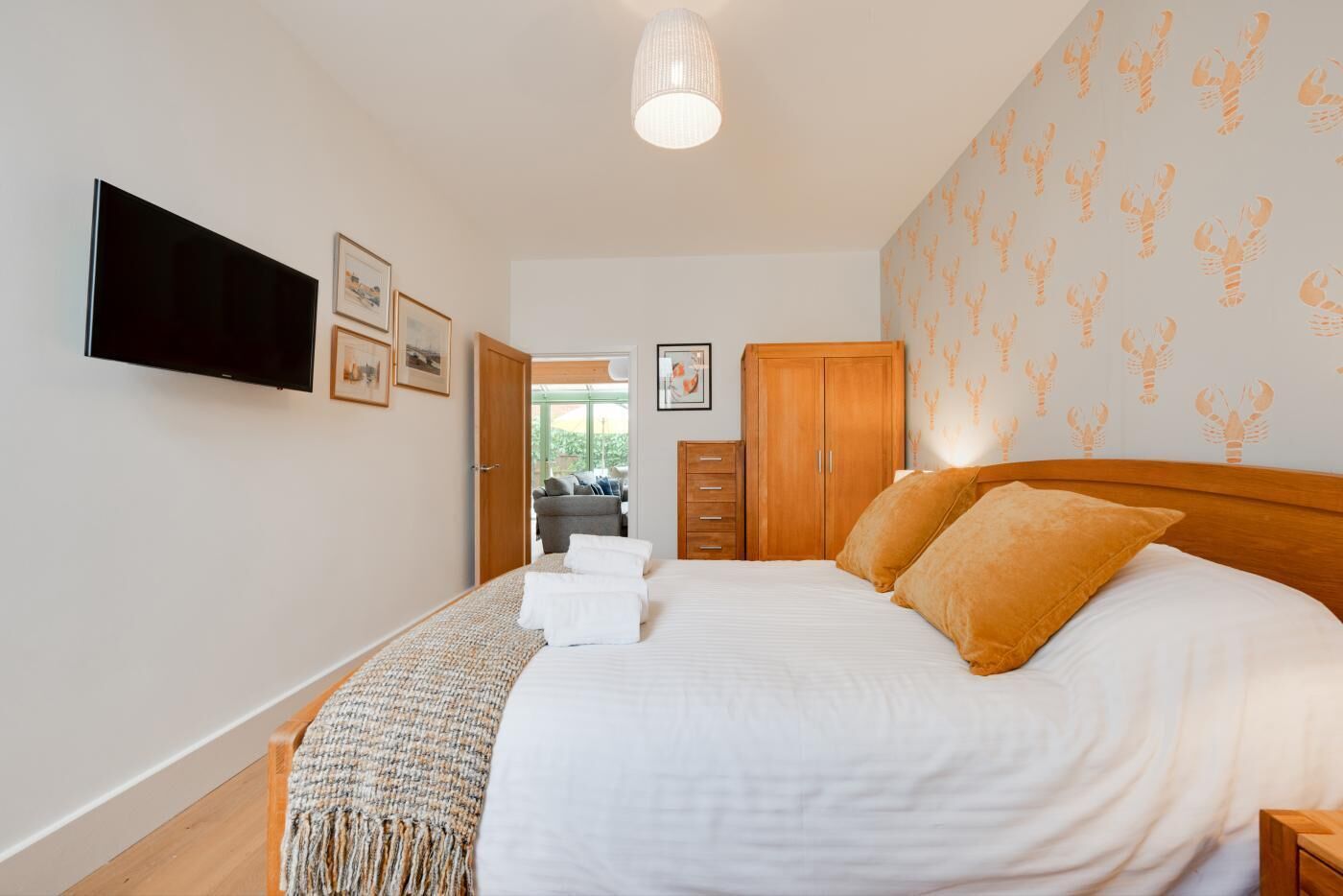 A bedroom with a bed, a television, a wardrobe, and a door leading to another room.